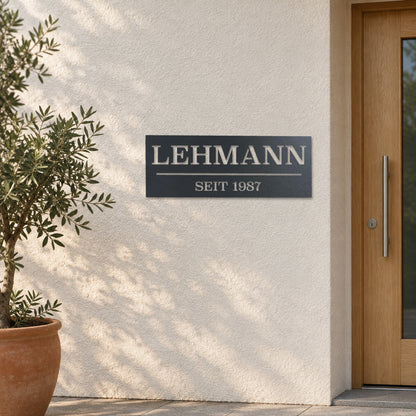 Edelstahl Hausnummernschild personalisiert – Hausschild „SEIT 1987 Lehmann“ an heller Putzwand, Edelstahl Anthrazit RAL 7016 · WesterWerk