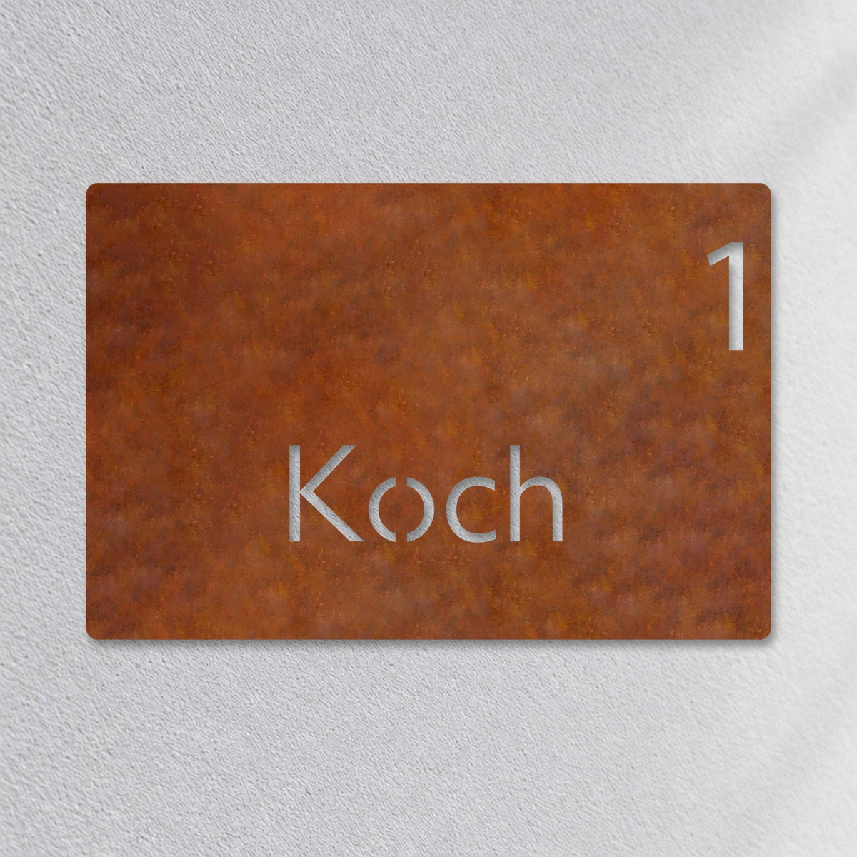 Edelstahl Hausnummernschild personalisiert – Moderne Nummer- und Namensschild „1 Koch“ Nahaufnahme an der Fassade, Edelstahl Cortenstahl · WesterWerk