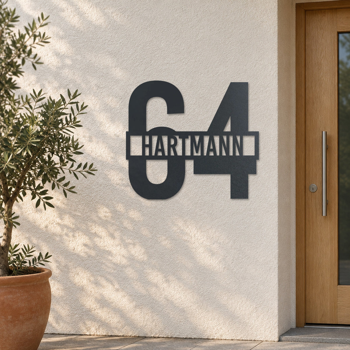 Edelstahl Hausnummernschild personalisiert – Name vor der Nummer „64 Hartmann“ an heller Putzwand, Edelstahl Anthrazit RAL 7016 · WesterWerk