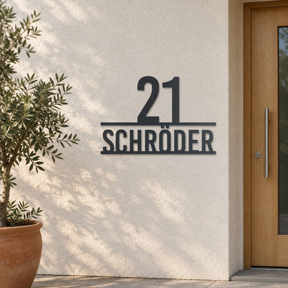 Edelstahl Hausnummernschild personalisiert – Stolze Nummer auf Namen „21 Schröder“ an heller Putzwand, Edelstahl Anthrazit RAL 7016 · WesterWerk
