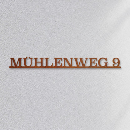 Edelstahl Straßenschild mit Hausnummer personalisiert – Einzeiliges Straßenschild „Mühlenweg 9“ Nahaufnahme an der Fassade, Cortenstahl Edelrost · WesterWerk