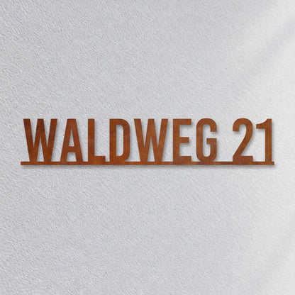 Edelstahl Straßenschild mit Hausnummer personalisiert – Straßenschild mit Hausnummer auf einer Linie „Waldweg 21“ Nahaufnahme an der Fassade, Cortenstahl Edelrost · WesterWerk